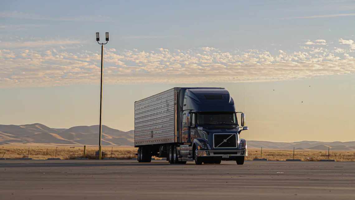 An articulated truck on an open road at sunset